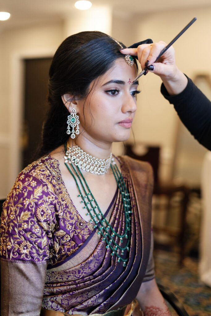 Makeup artist applying finishing touches to Advaitaa's makeup
