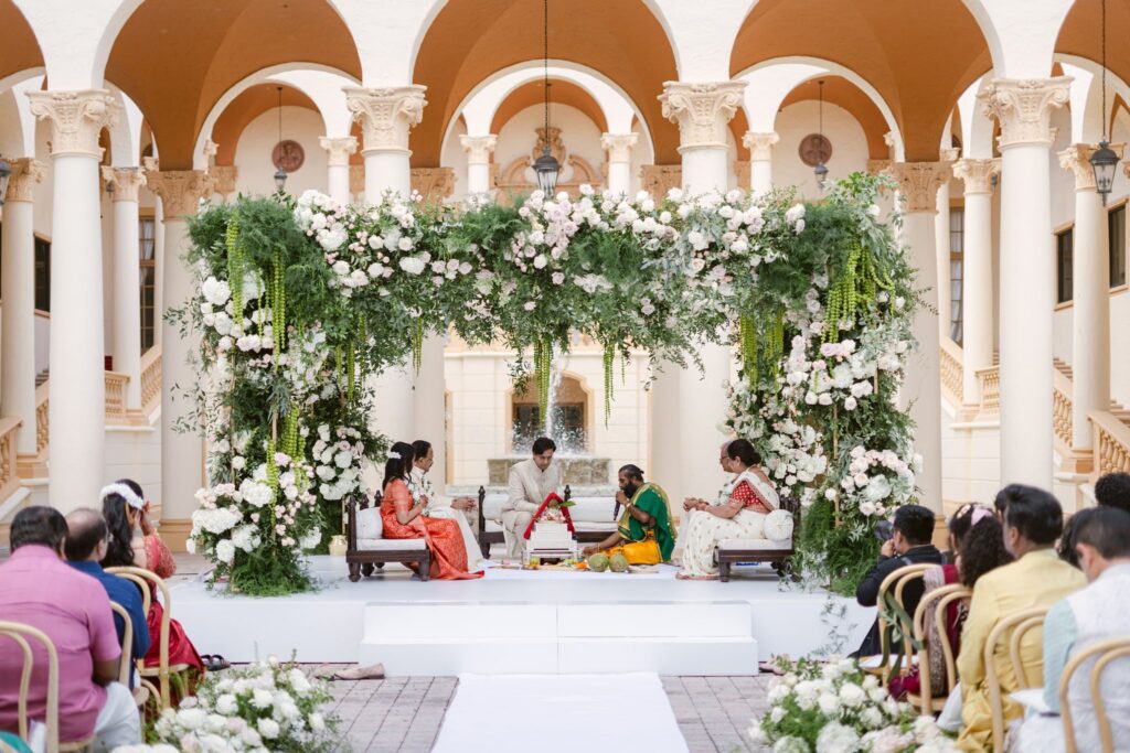 Wide view of the ceremony with guests seated under the arches