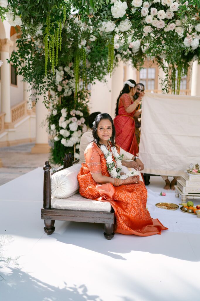 Woman in an orange saree seated on the mandap