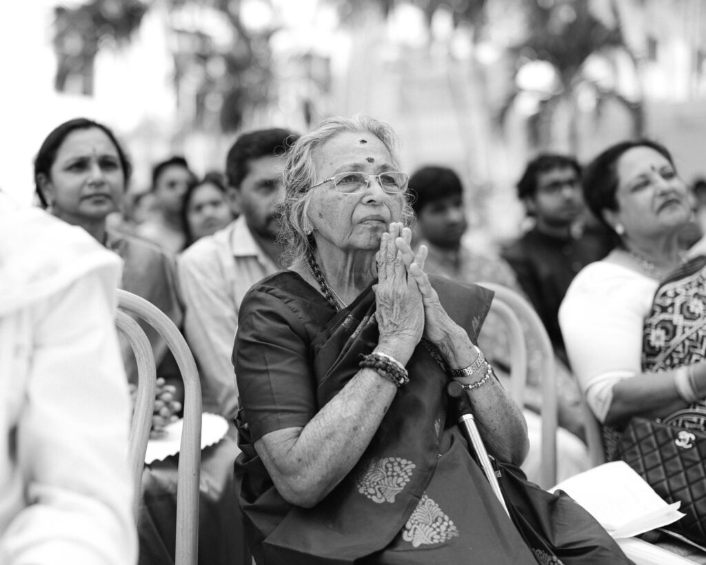 Grandmother with hands in prayer during the ceremony in black and white