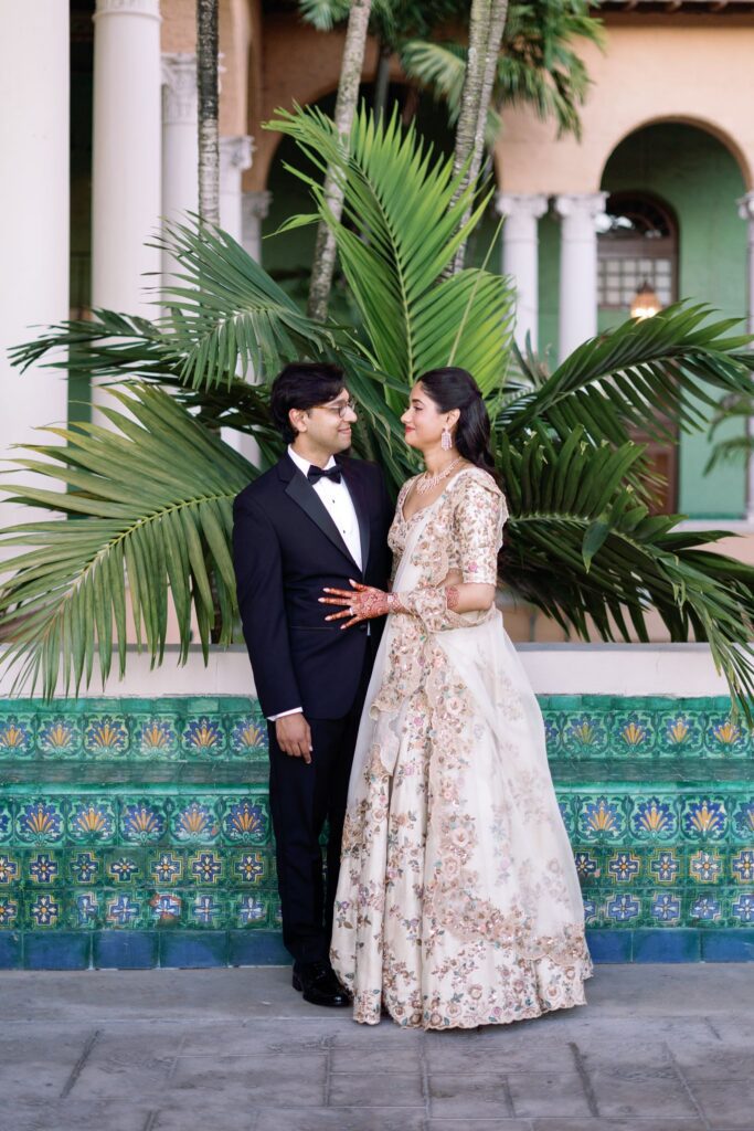 Couple embracing in front of palms and teal tile at The Biltmore Hotel