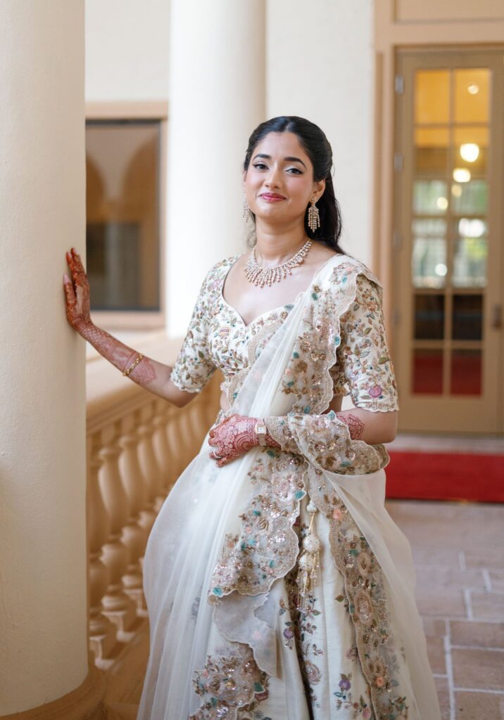Advaitaa in an ivory and gold sparkling lehenga choli posing against a column