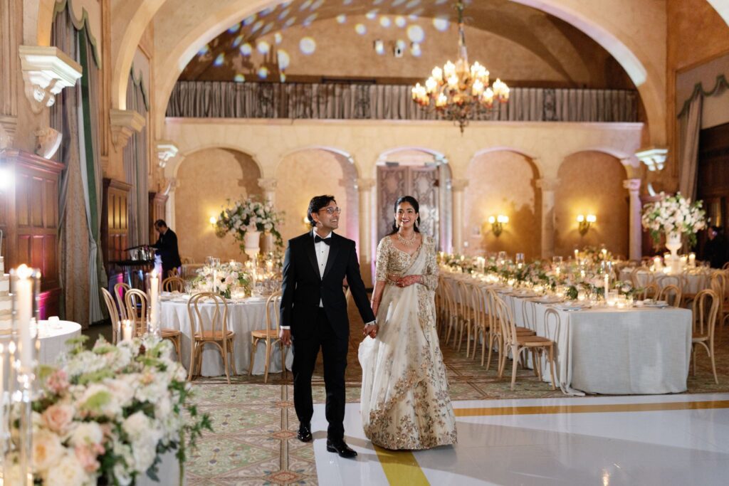 Advaitaa and Tejus walking through the candlelit Granada Ballroom