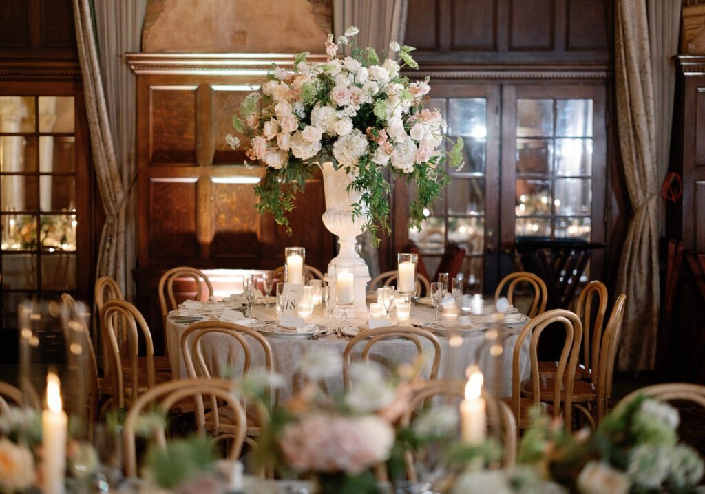 Round reception table with a tall floral centerpiece and candles