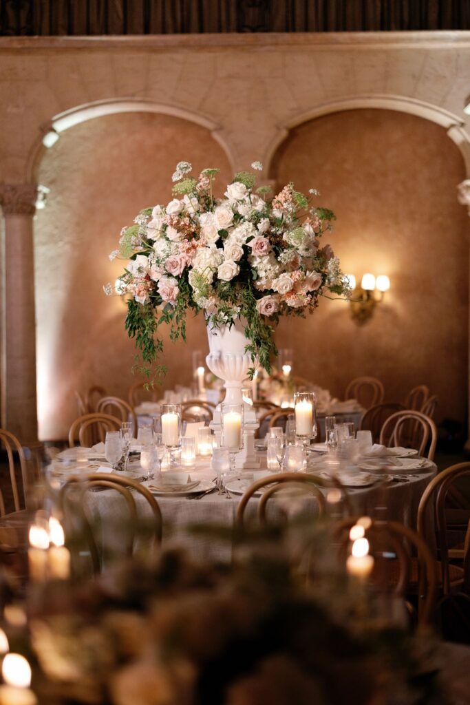 Blush and ivory floral centerpiece glowing in candlelight