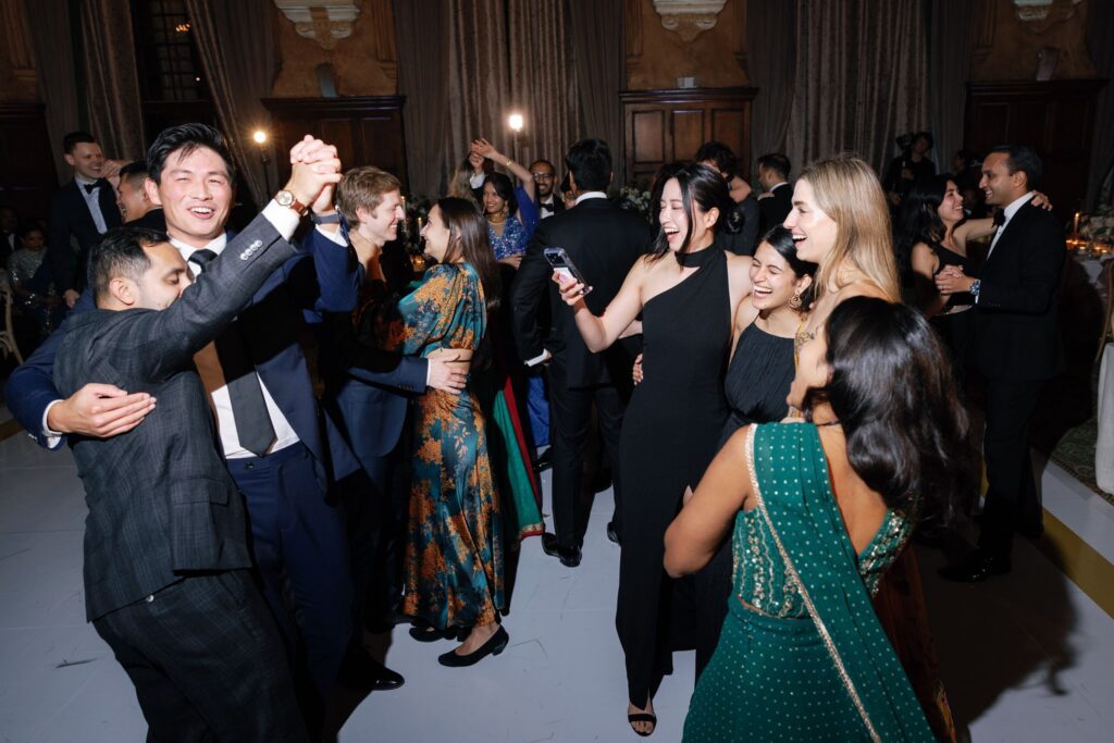 Guests dancing with arms raised on the packed dance floor