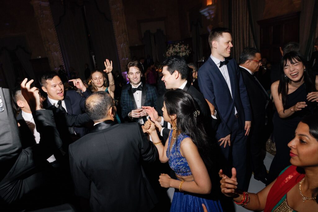 Crowded dance floor with guests in tuxedos and gowns dancing
