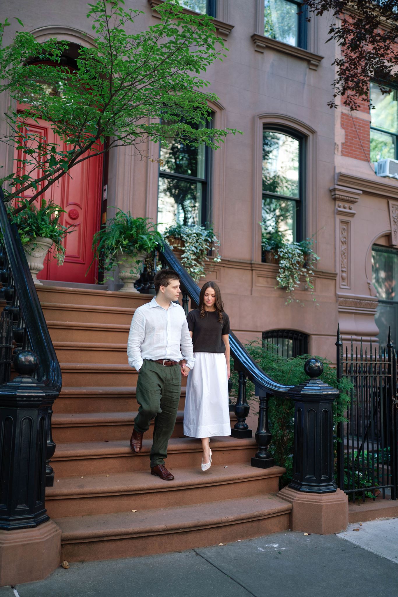 Haley and Jeremy walking down the step of a red-door brownstone, about to leave