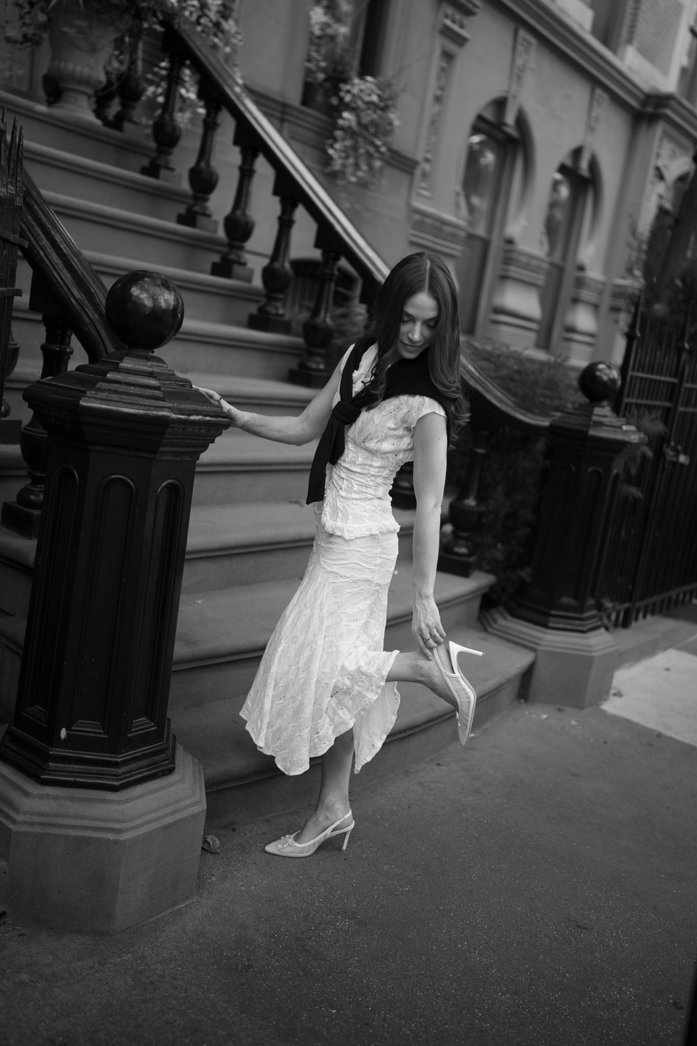 Haley readjusting her shoe on brownstone steps in West Village, New York City