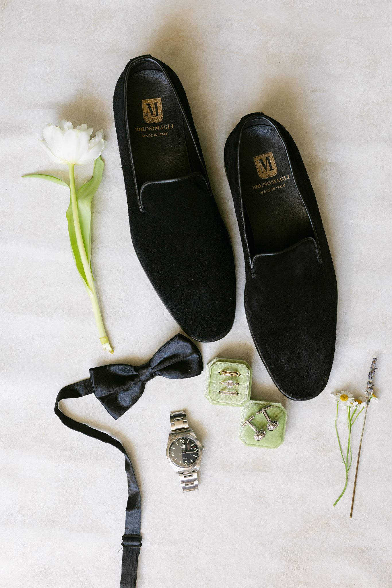 Groom's black bow tie, shoes, watch, cufflinks and rings styled with a mint ring box and flowers