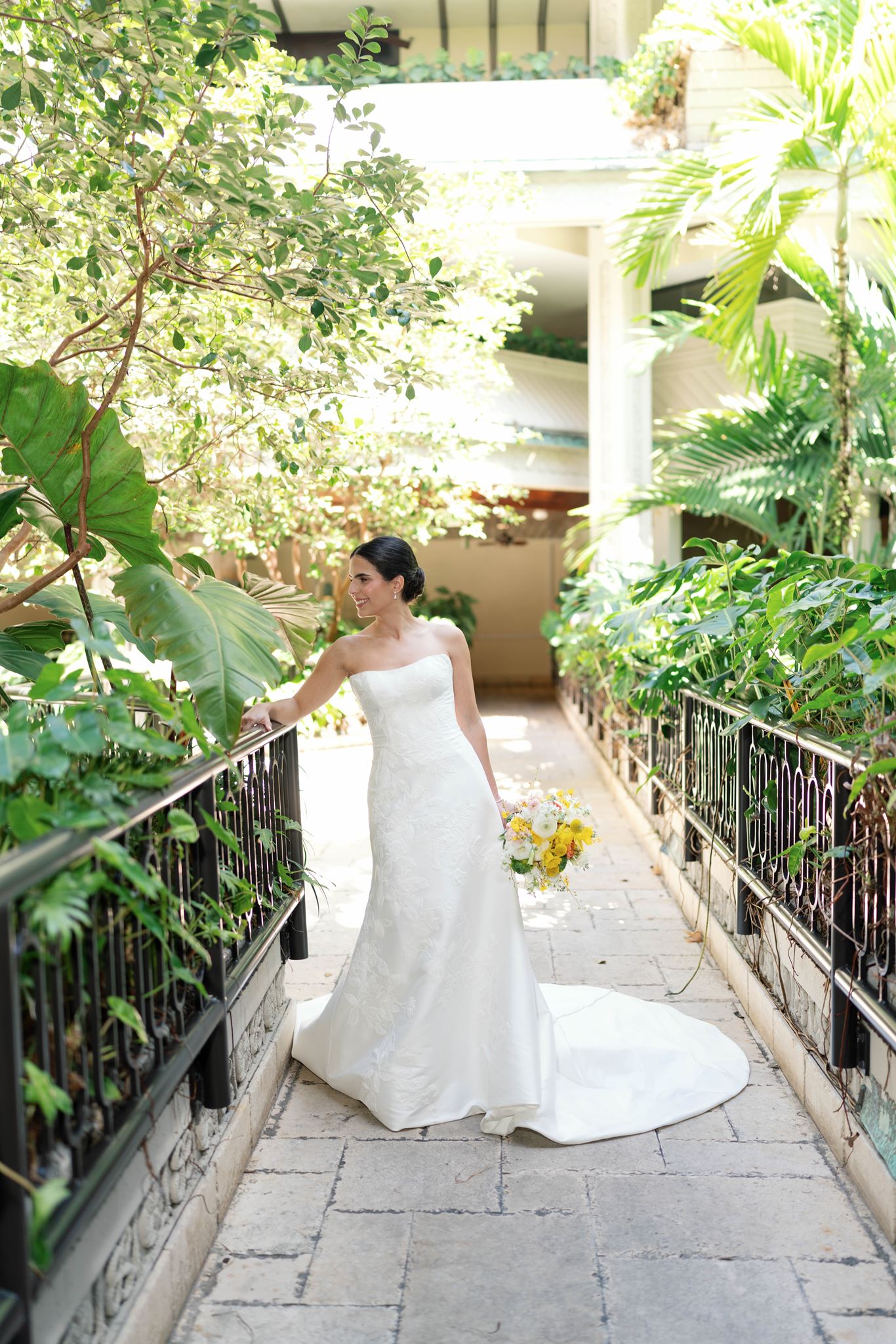 Ashley in her wedding gown walking along a garden path at the Mayfair Hotel