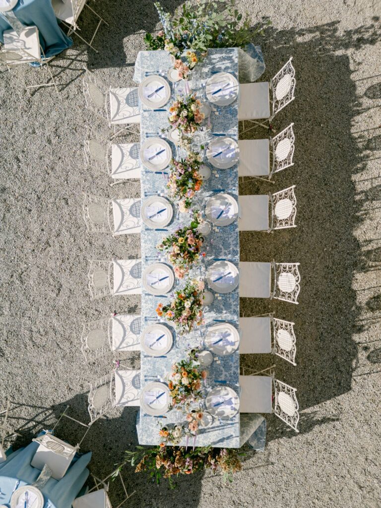 Aerial view of wedding reception setting with blue floral linen, plates and flowers