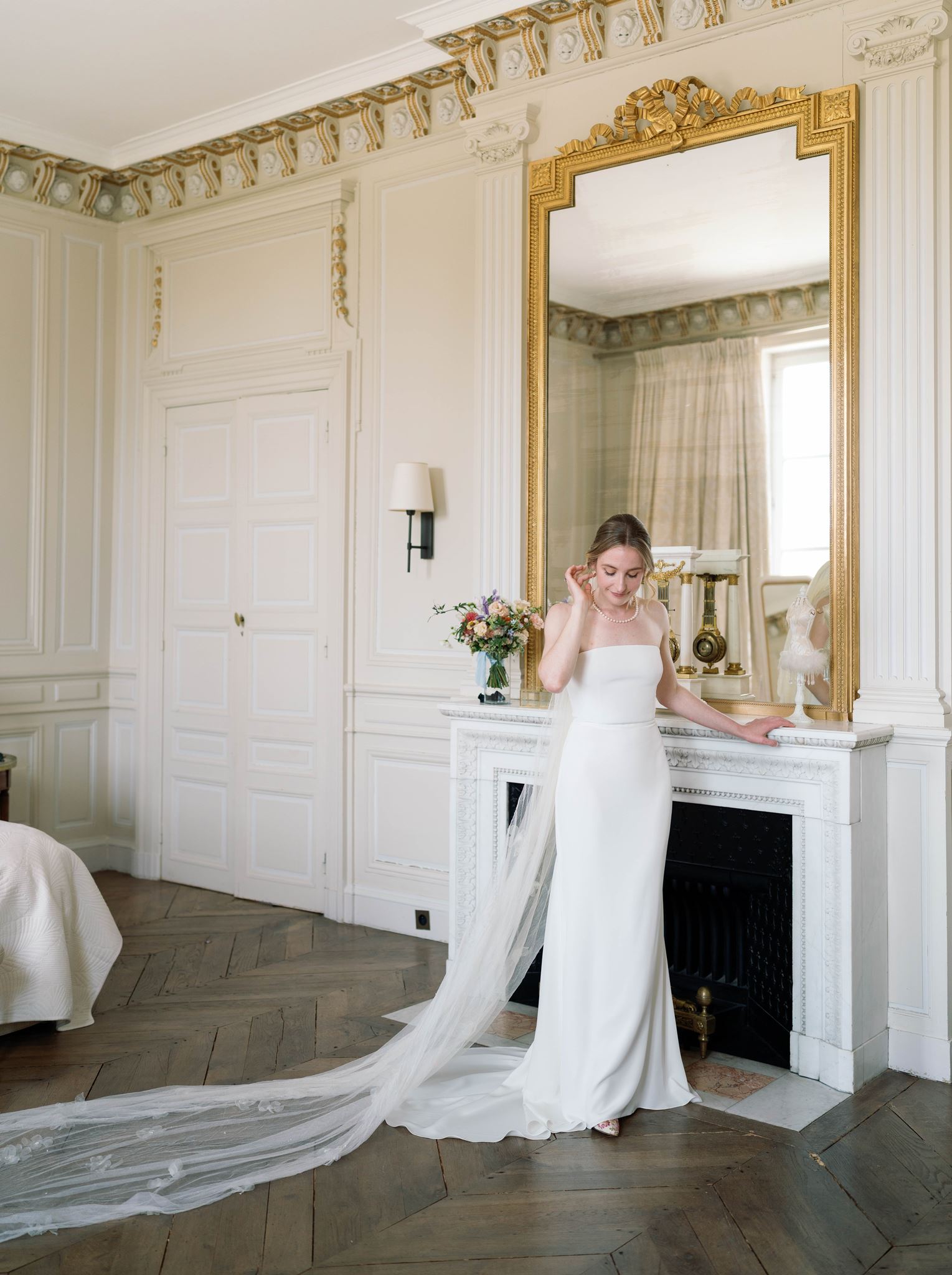 Portrait of Romy in her wedding gown beside the fireplace mirror