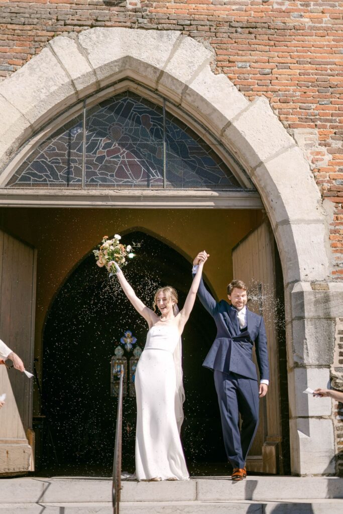 Romy and Jonathan walking out of the church hand in hand as guests throw dried lavender