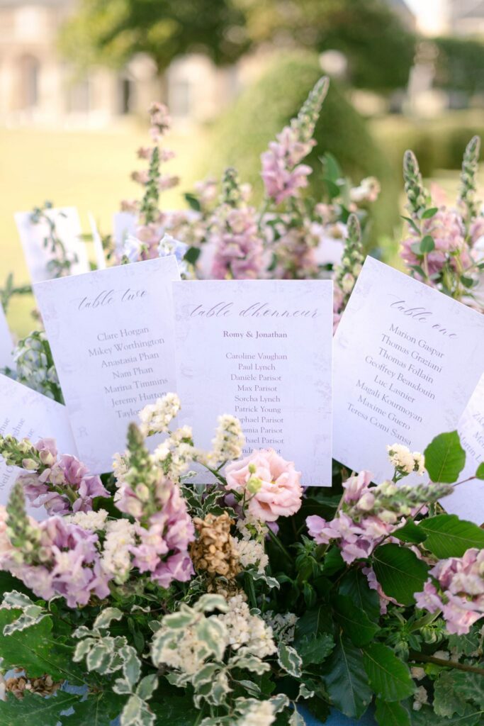 Guests seating chart in blush and pink flower bouquet on the château lawn