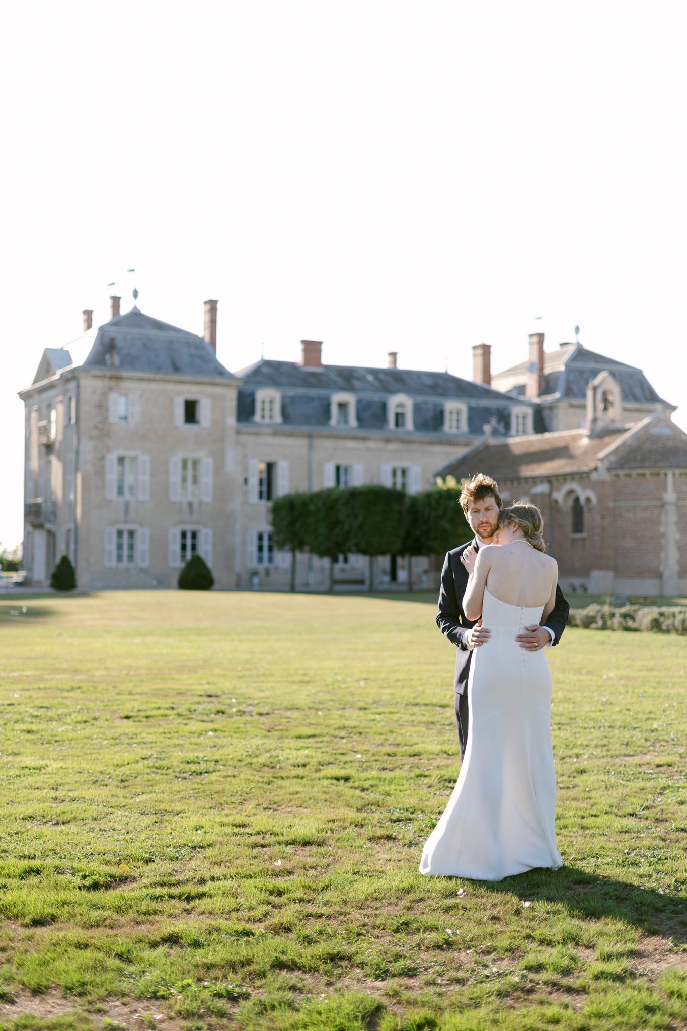Romy and Jonathan embracing each other in the lawn with Château de Varennes behind them