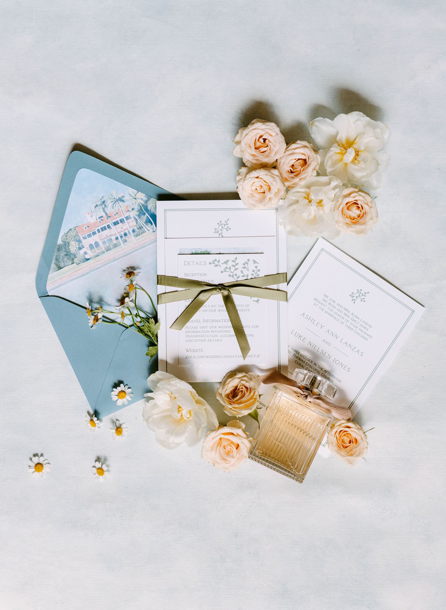 Wedding invitation suite with a blue envelope, ribbon and cream roses styled for Ashley and Luke's Miami wedding