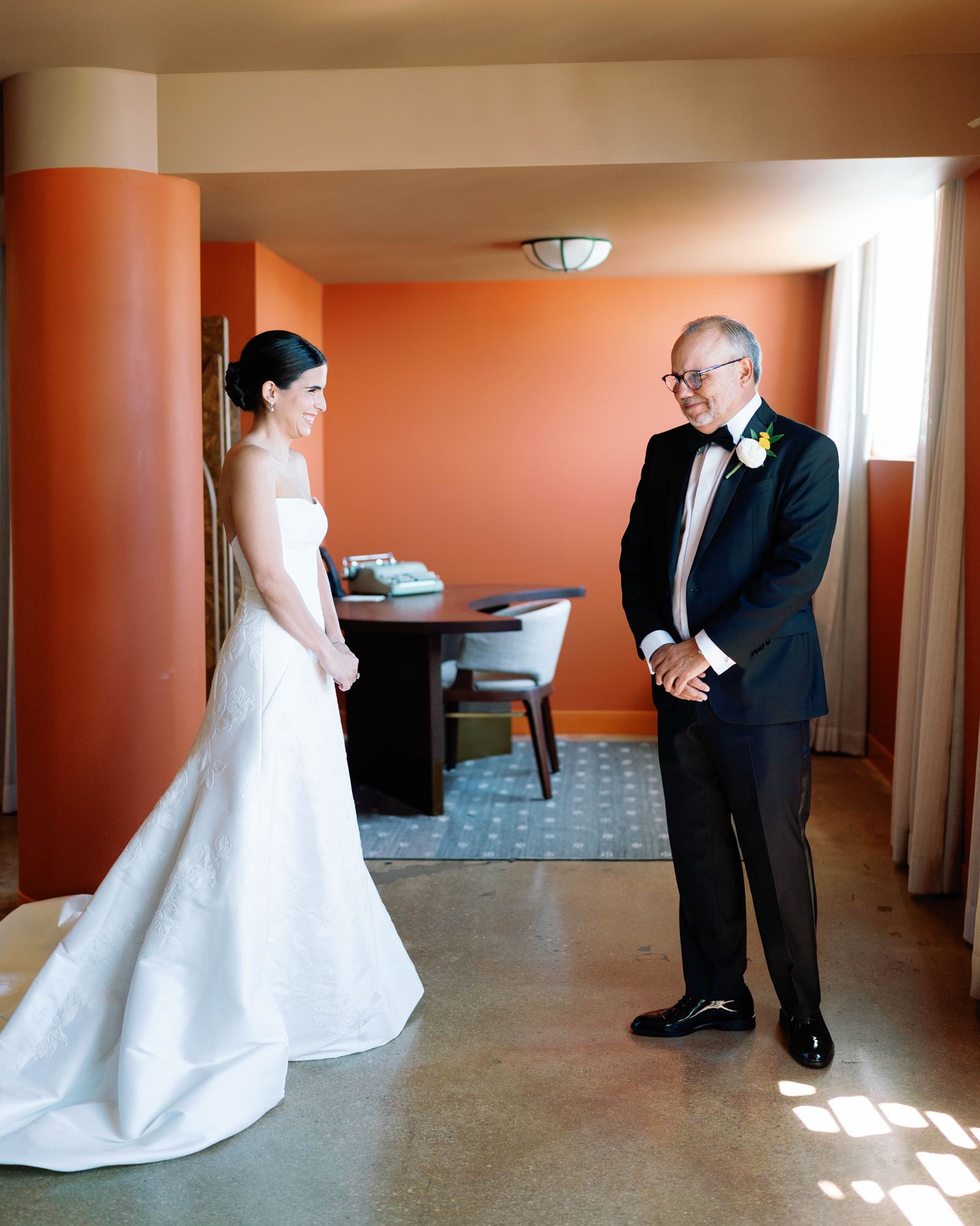 Bride and her father sharing a first look in an orange-walled Mayfair hotel suite