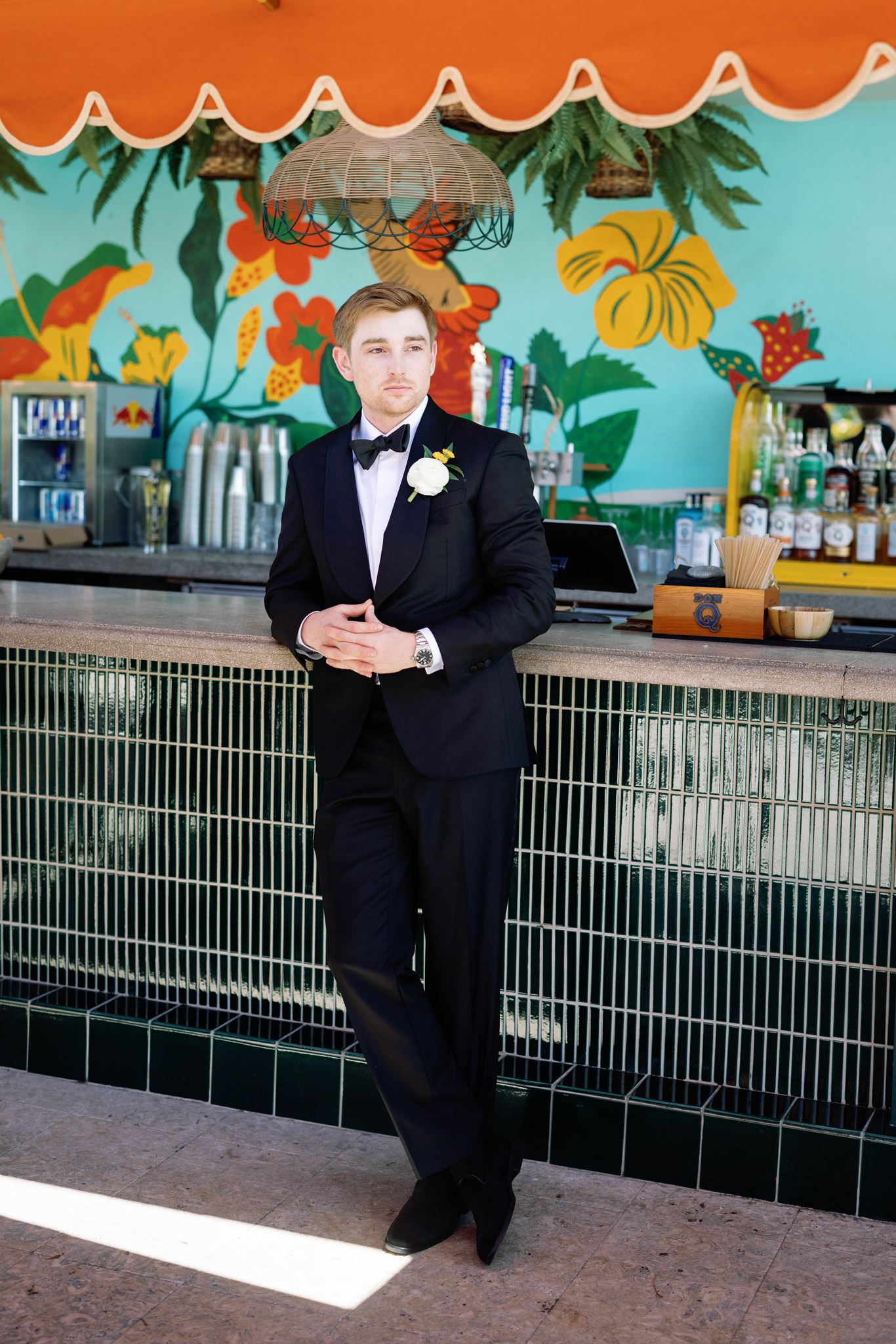 Luke leaning against a tiled bar in his black tuxedo at the Mayfair Hotel