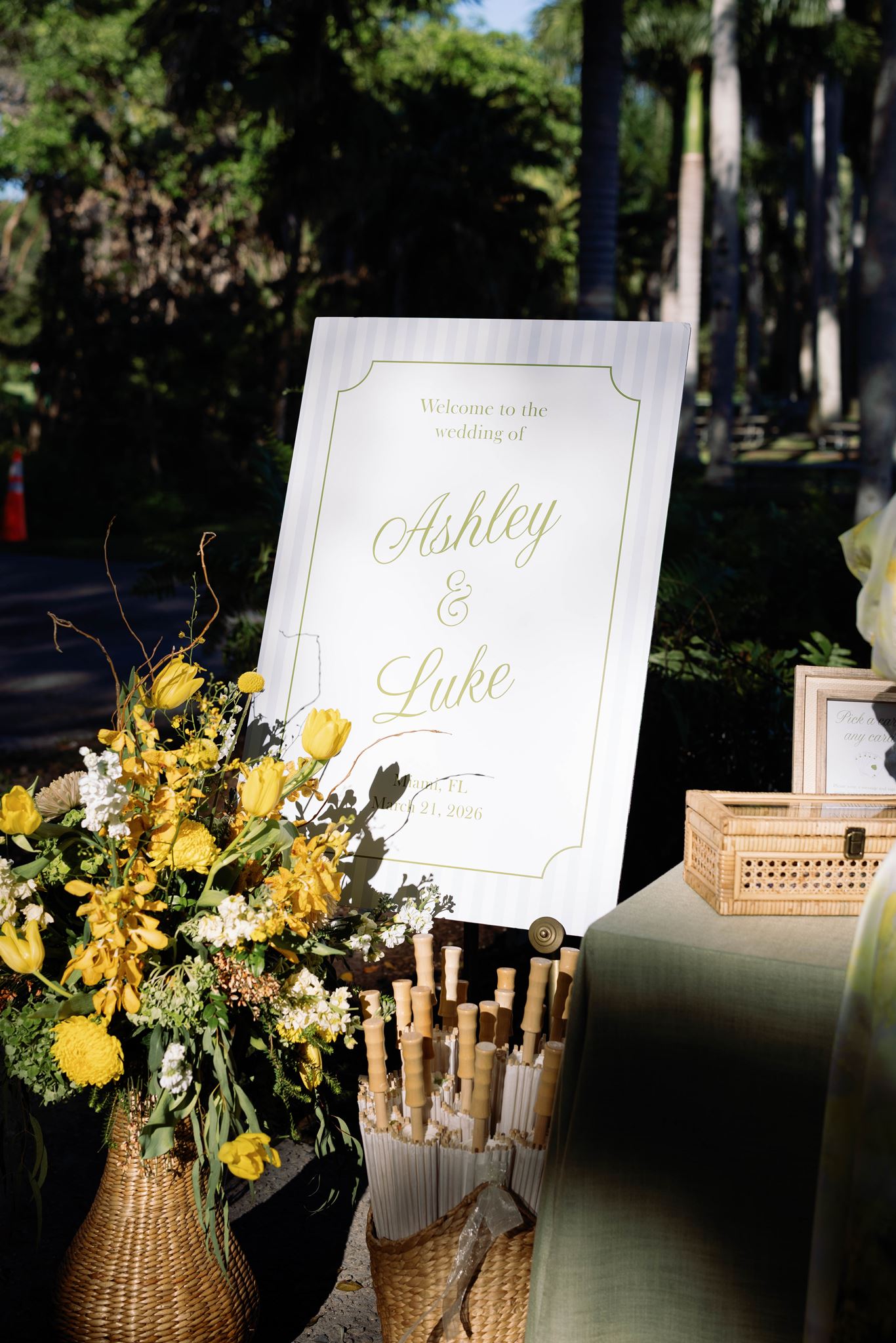Welcome sign for Ashley and Luke with yellow flowers and parasols for guests