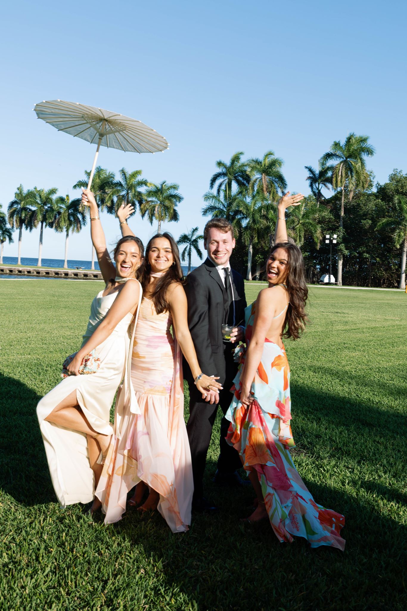 Guests laughing with a paper parasol on the lawn overlooking Biscayne Bay
