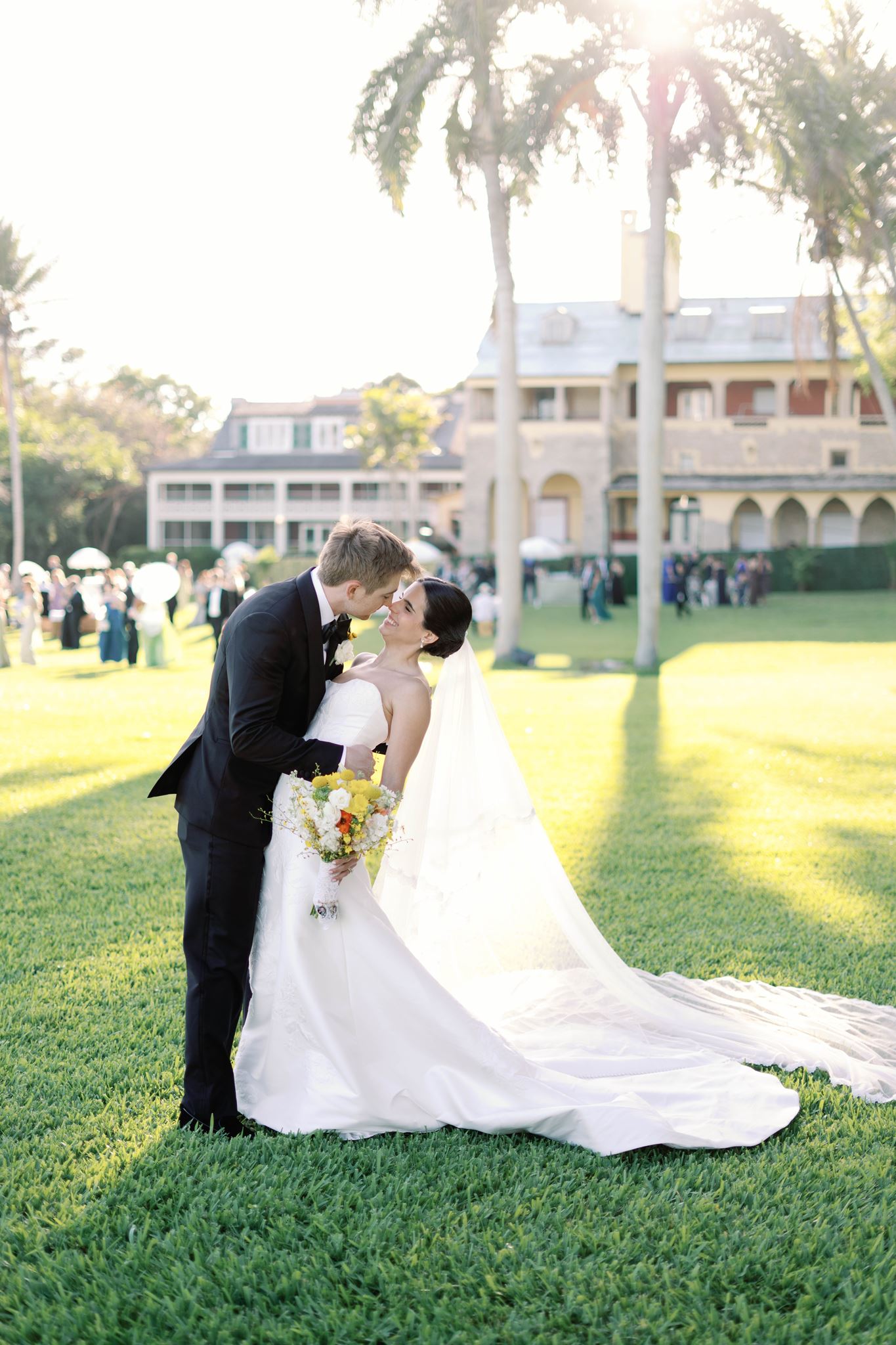 Ashley and Luke kissing on the lawn with the Deering Estate behind them