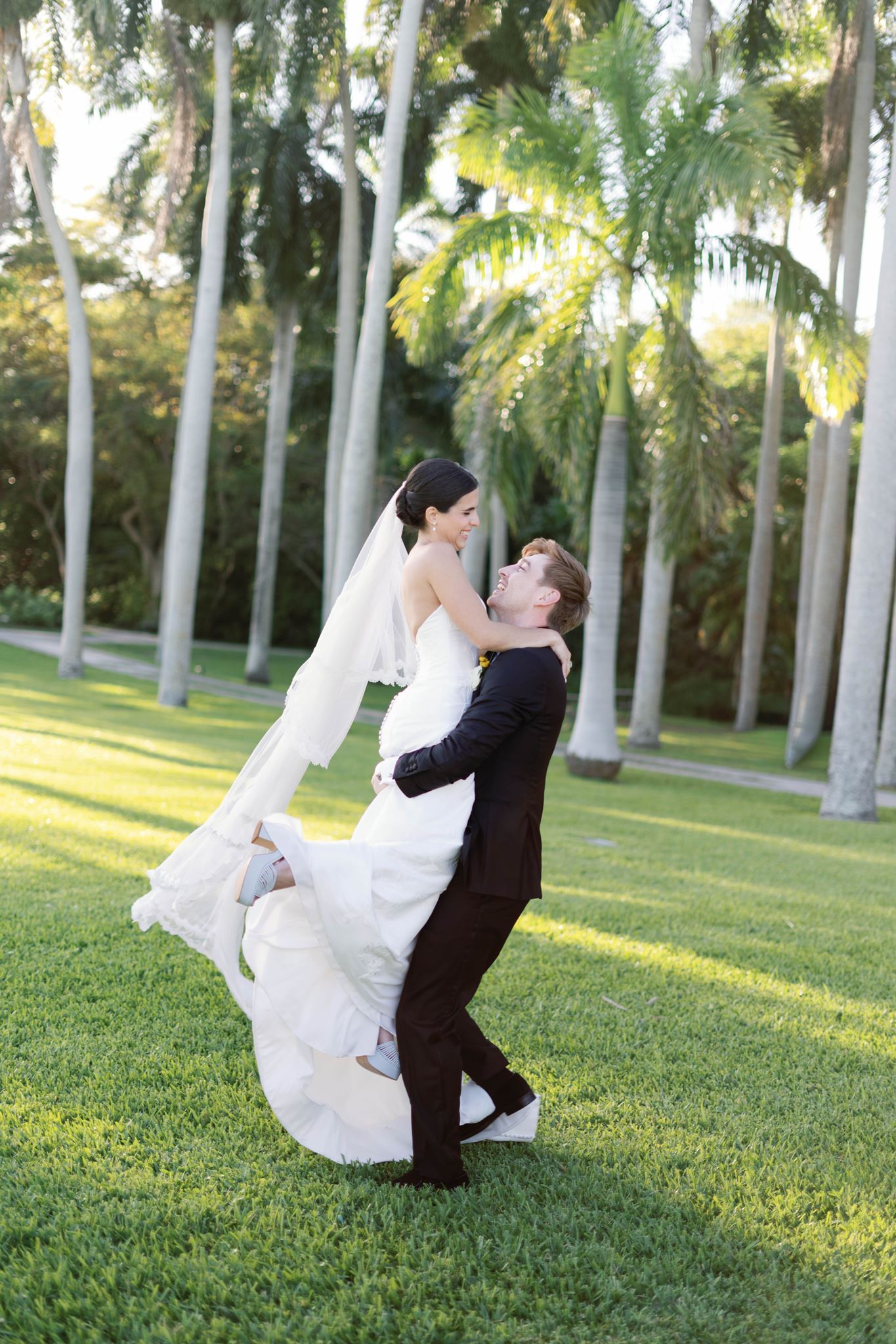 Luke lifting Ashley as her veil swirls in the golden light