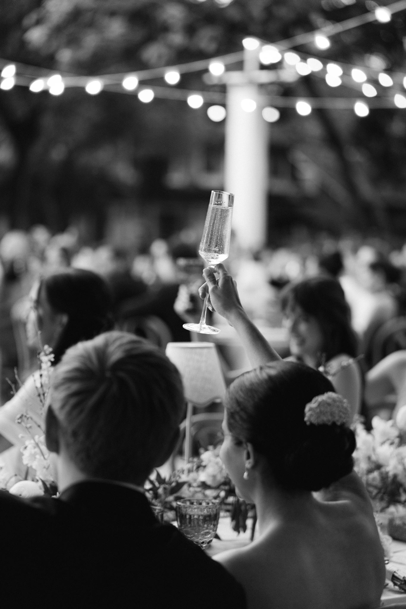 Guest raising a champagne glass during toasts at the reception in black and white