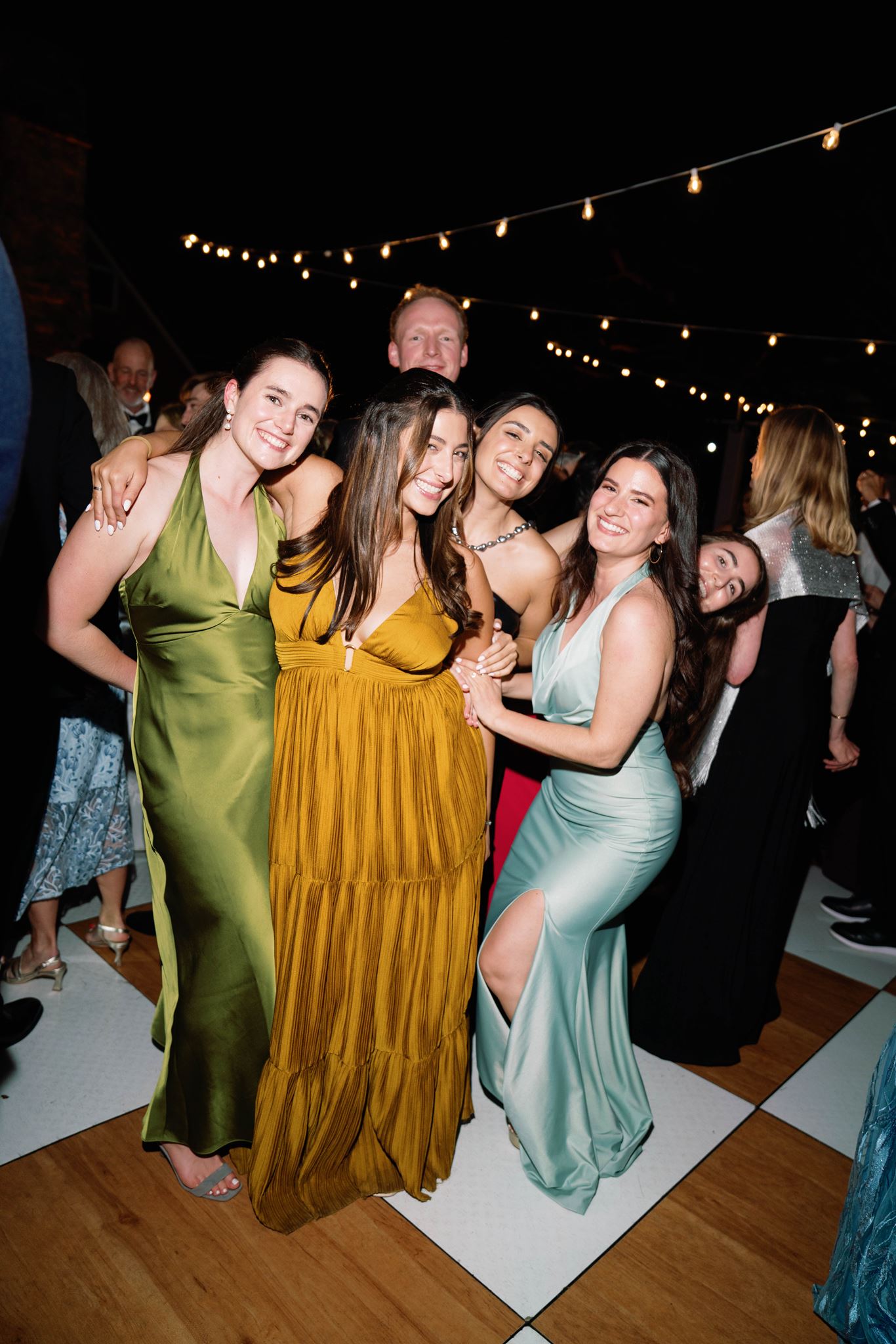 Guests in colorful gowns dancing together at the reception