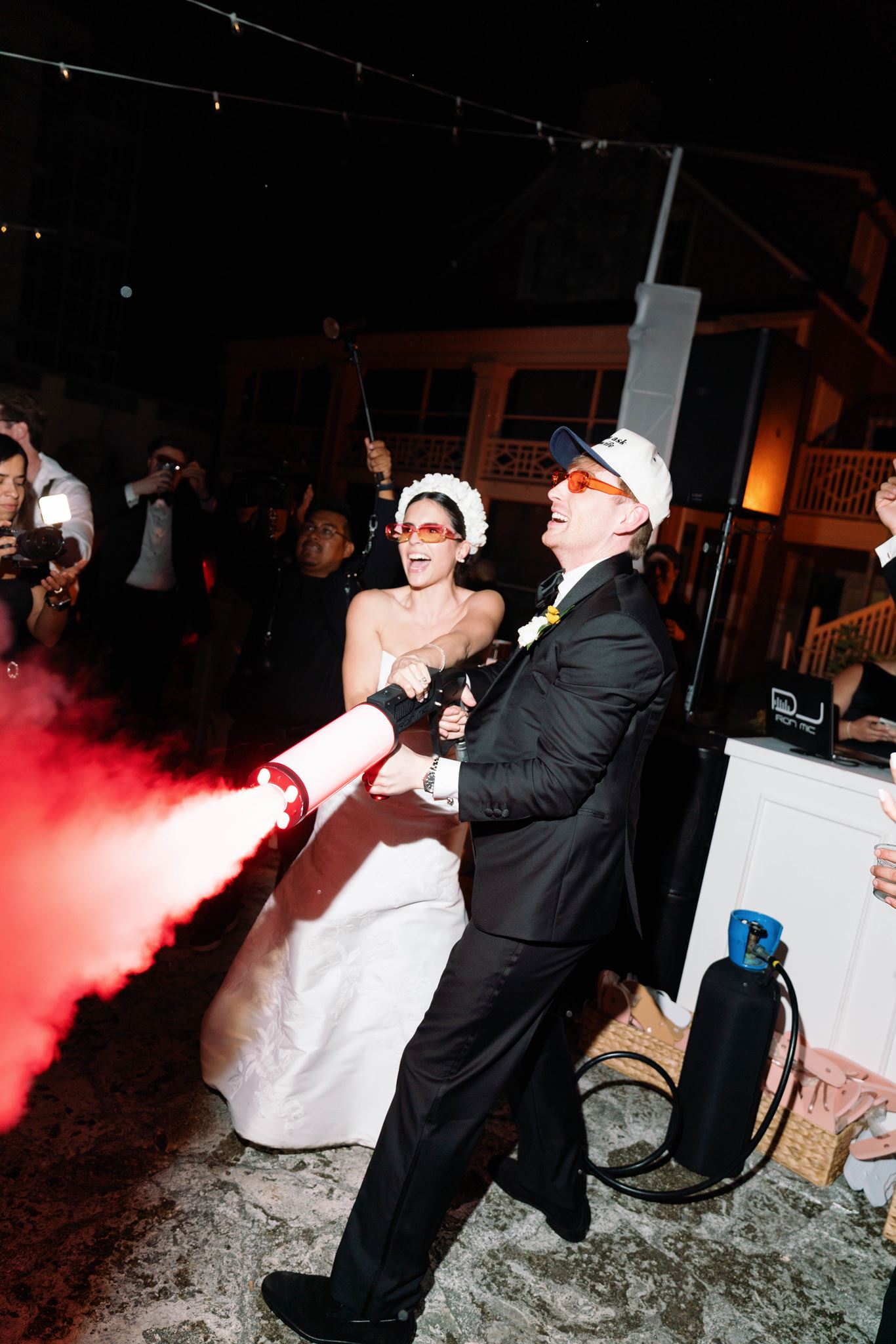 Luke blasting pink smoke from a smoke gun while Ashley dances beside him