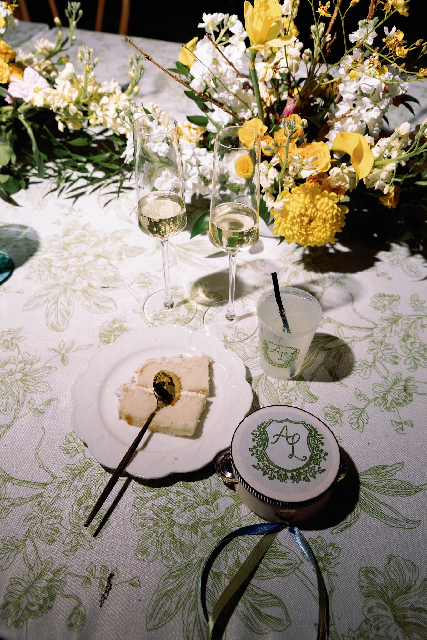Place setting with a monogrammed favor on green toile linen