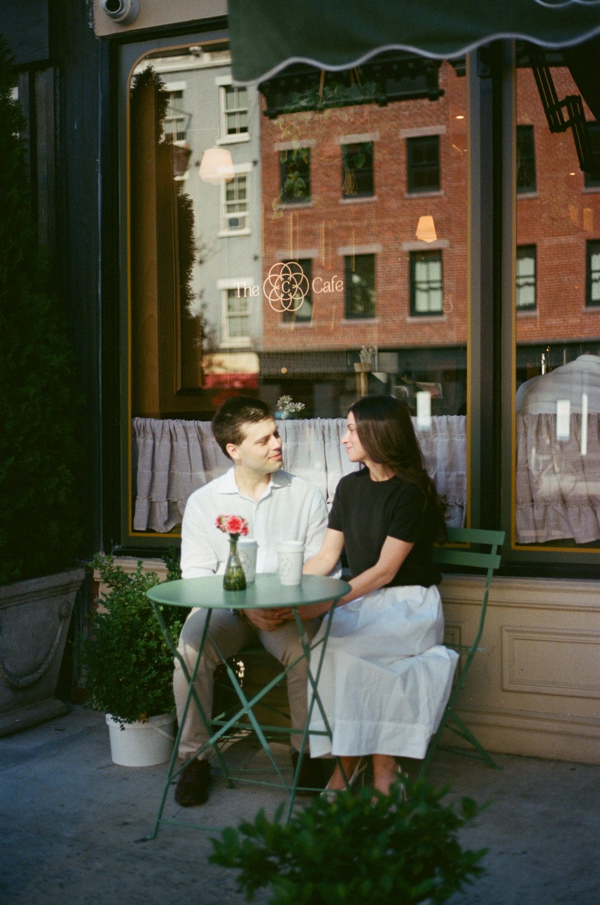 Film photo of Haley and Jeremy sharing coffee at a sidewalk café table in the West Village