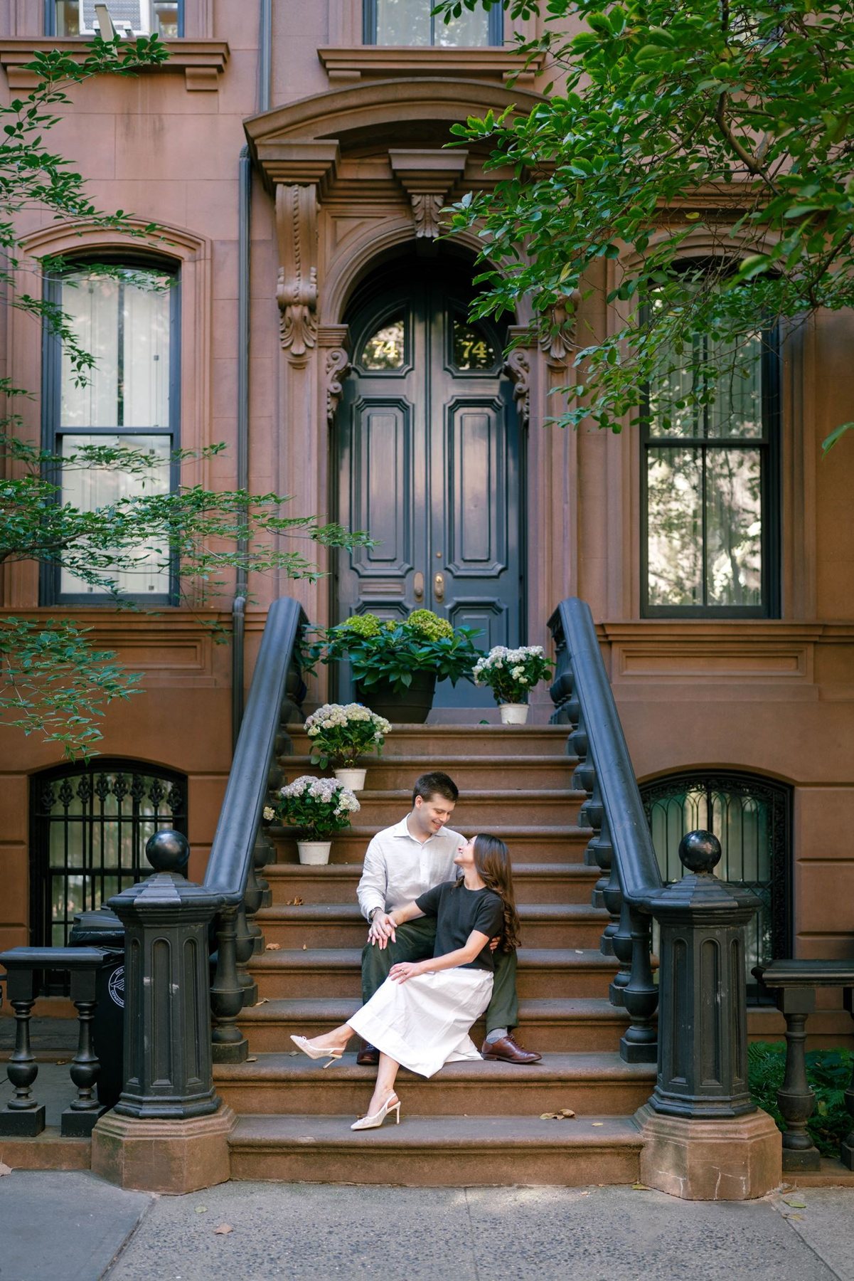 Haley and Jeremy sitting together on the steps of a West Village brownstone, framed by the arched front door