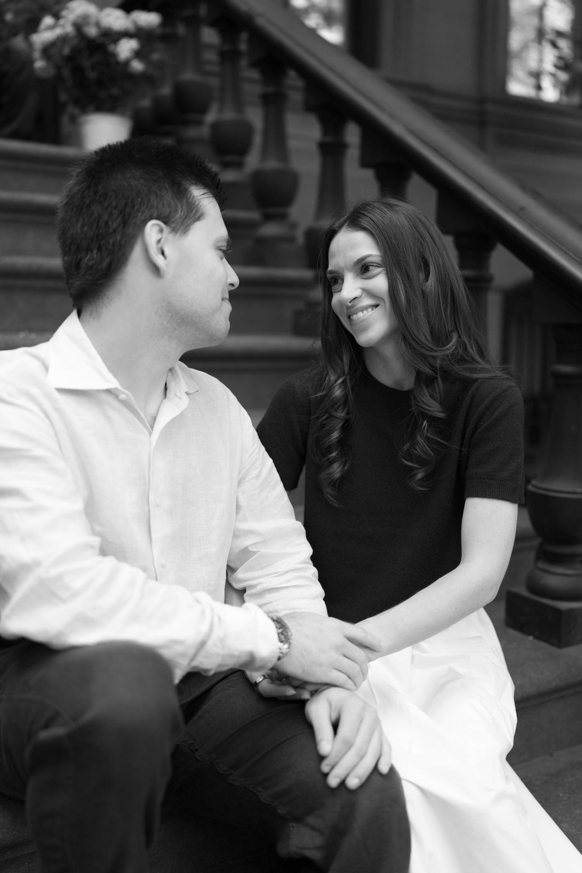 Black and white portrait of Haley and Jeremy laughing together on a brownstone stoop