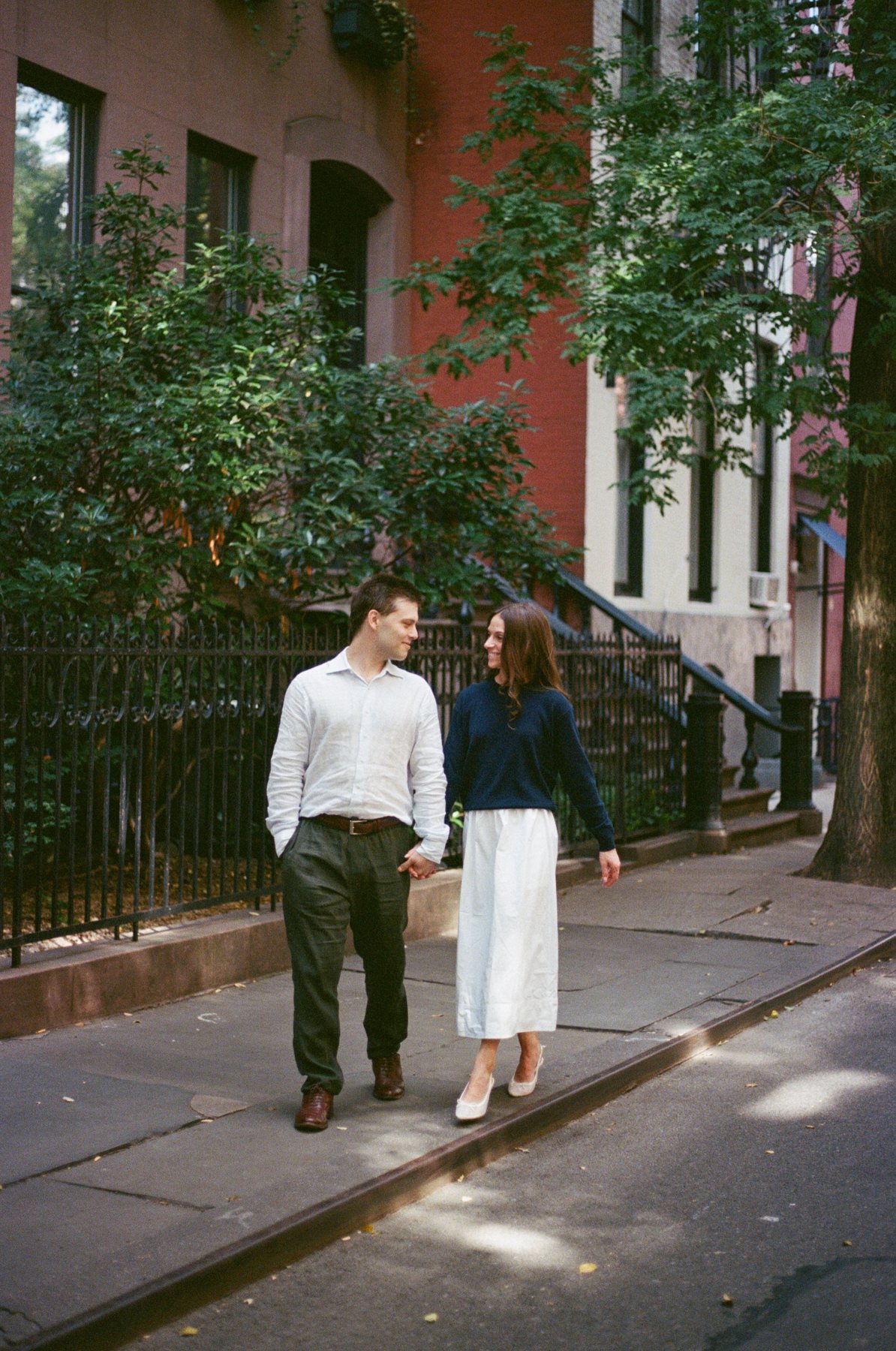 Film photo of Haley and Jeremy strolling a tree-lined West Village sidewalk
