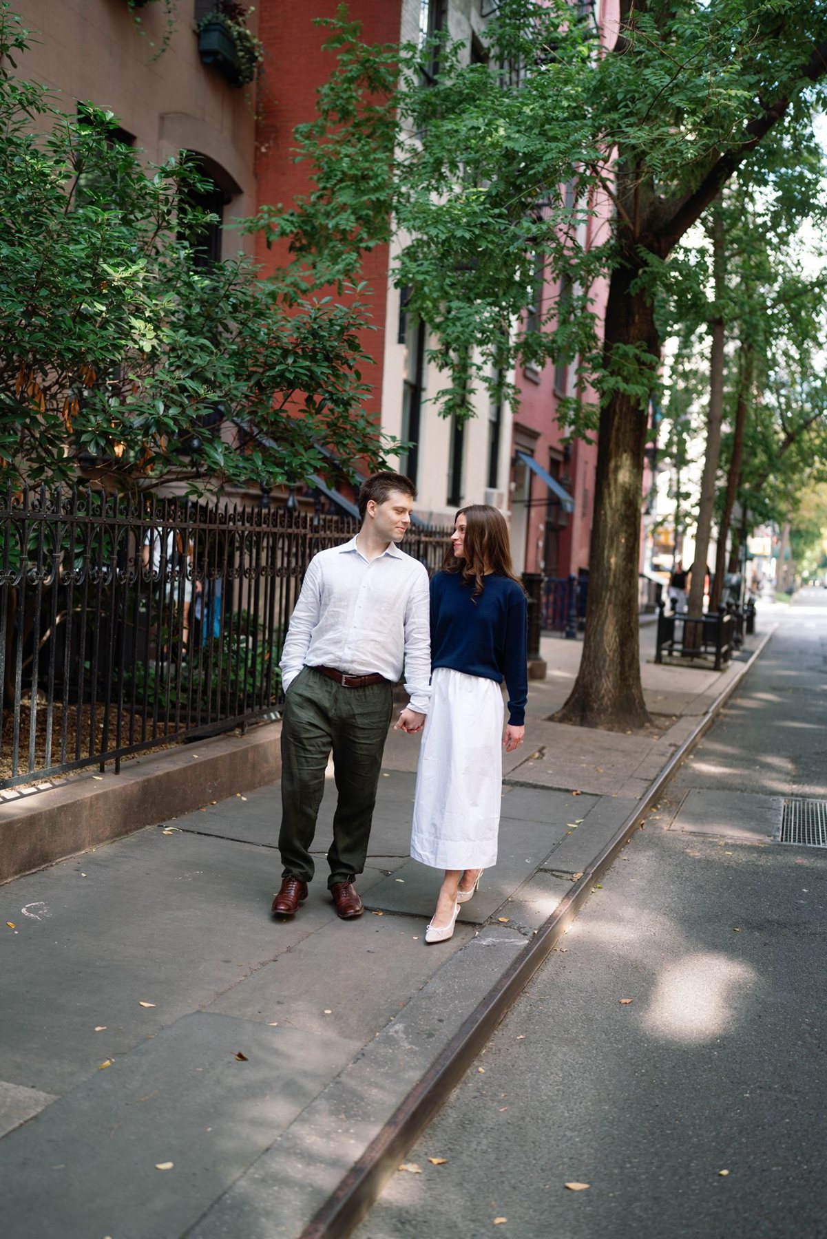 Haley and Jeremy walking hand in hand down a leafy West Village street